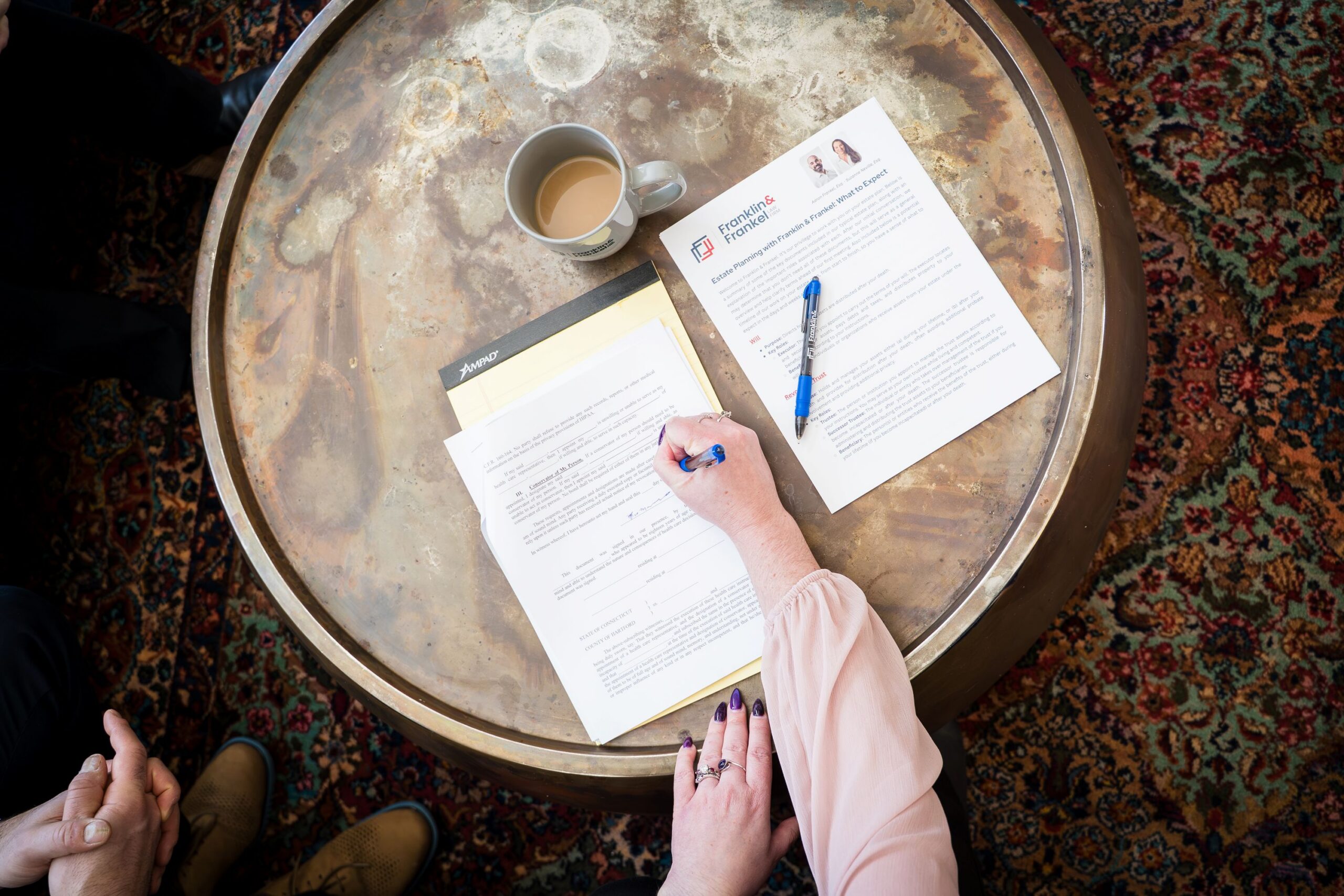 overhead view of a woman signing legal documents on a round table